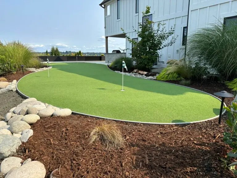 Photo of a putting green next to a house surrounded by barked garden areas