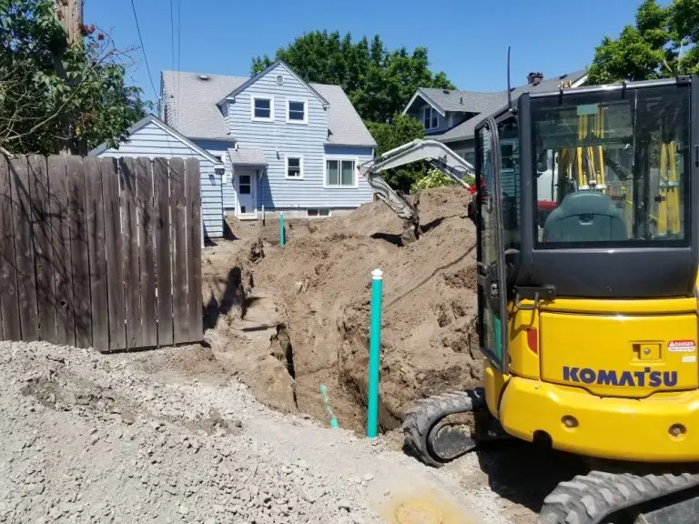 Excavator digging in front of a home